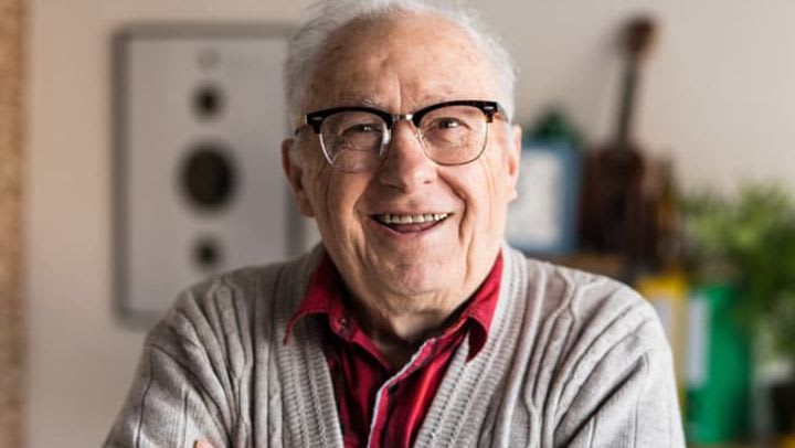 Smiling elderly man wearing glasses indoors