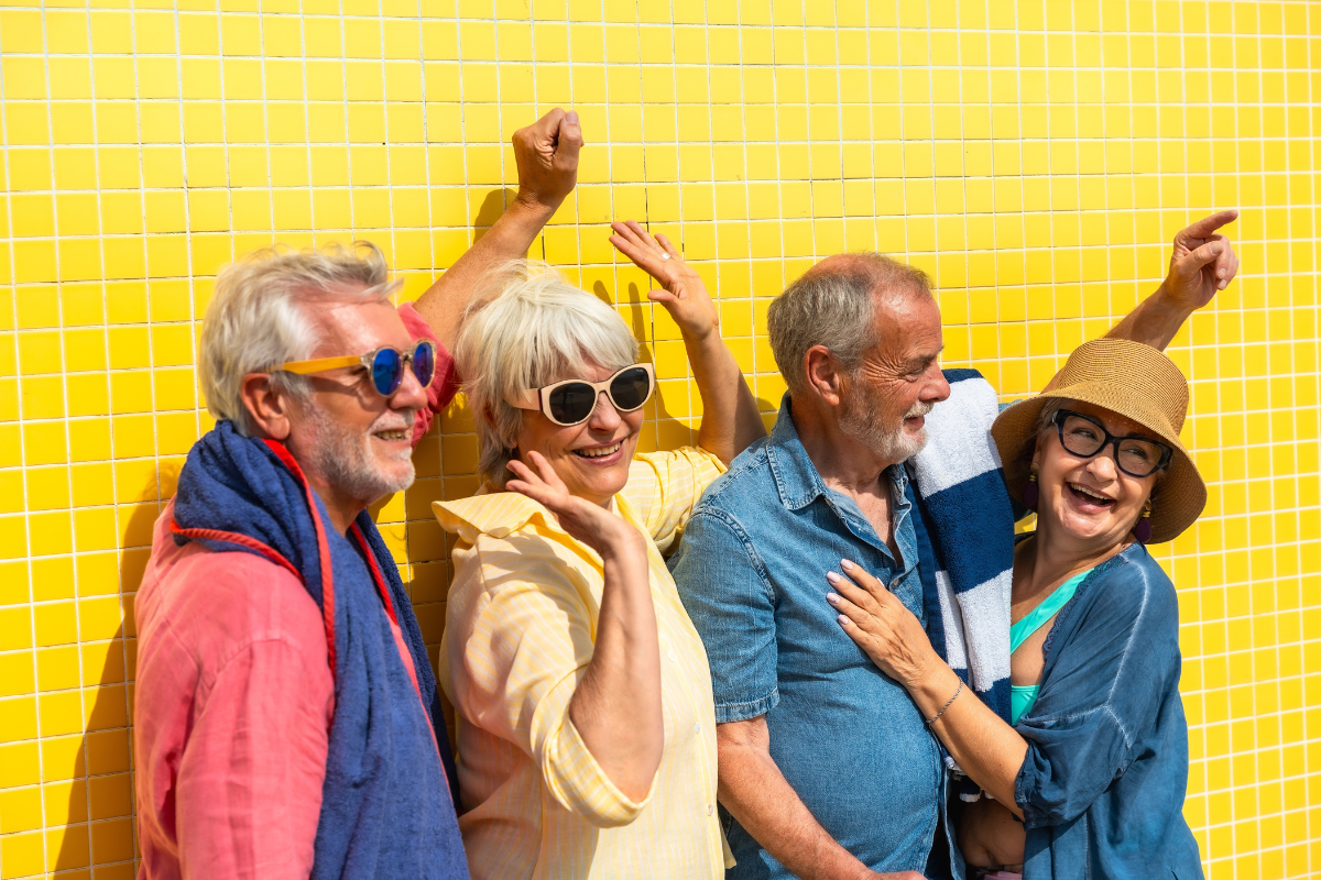 Four seniors smiling against bright yellow tiled wall