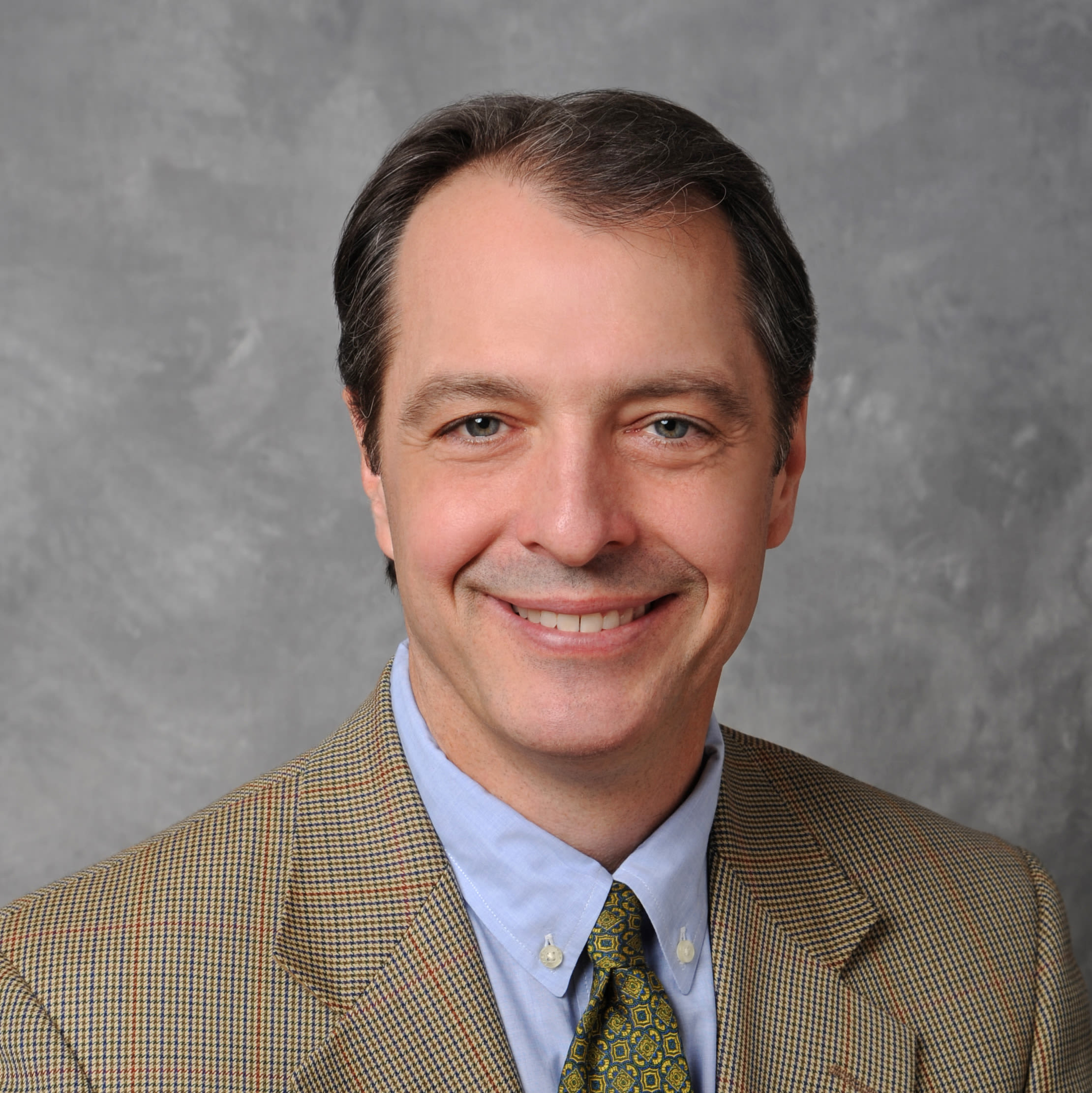 Smiling man in suit against gray backdrop