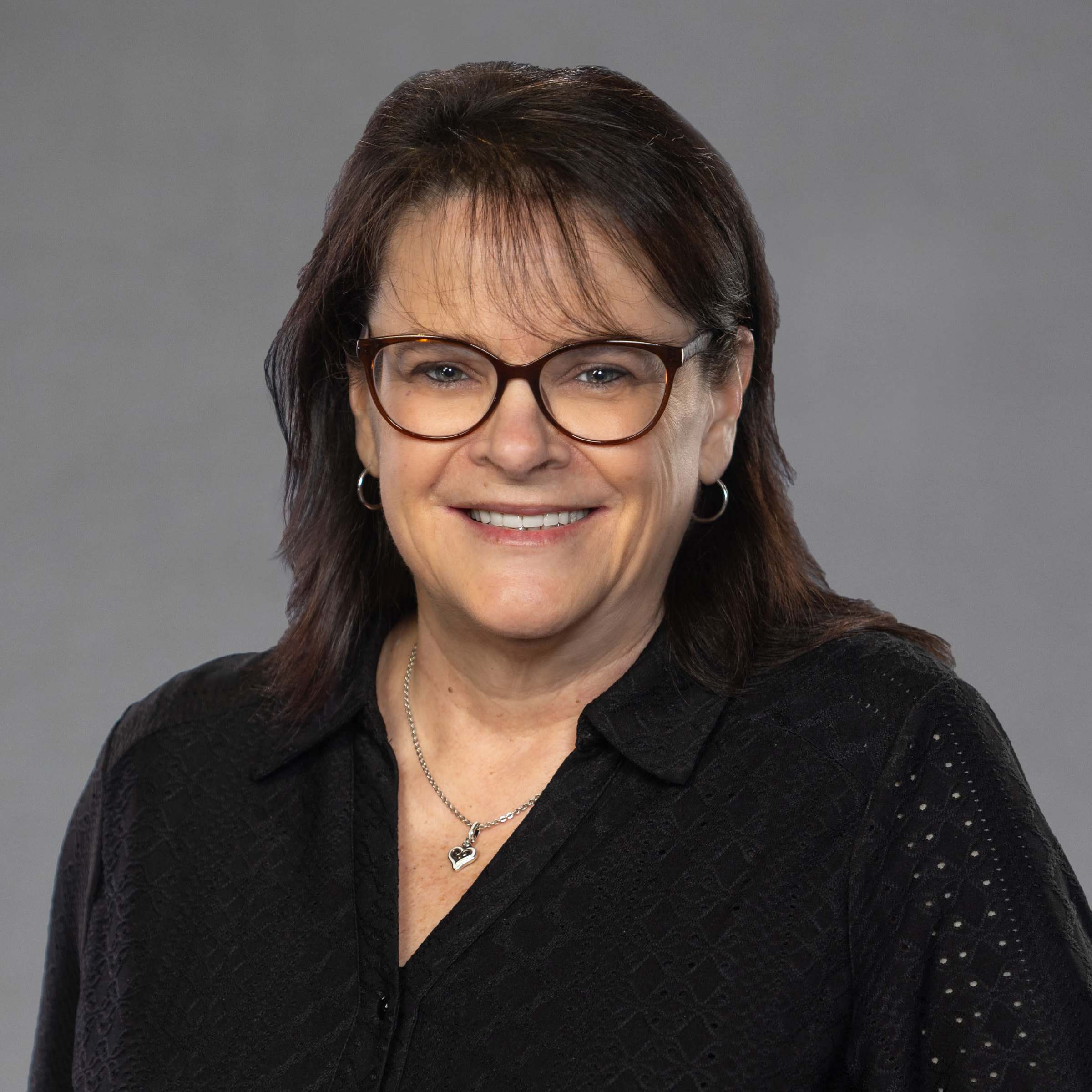 Smiling woman with glasses against gray background