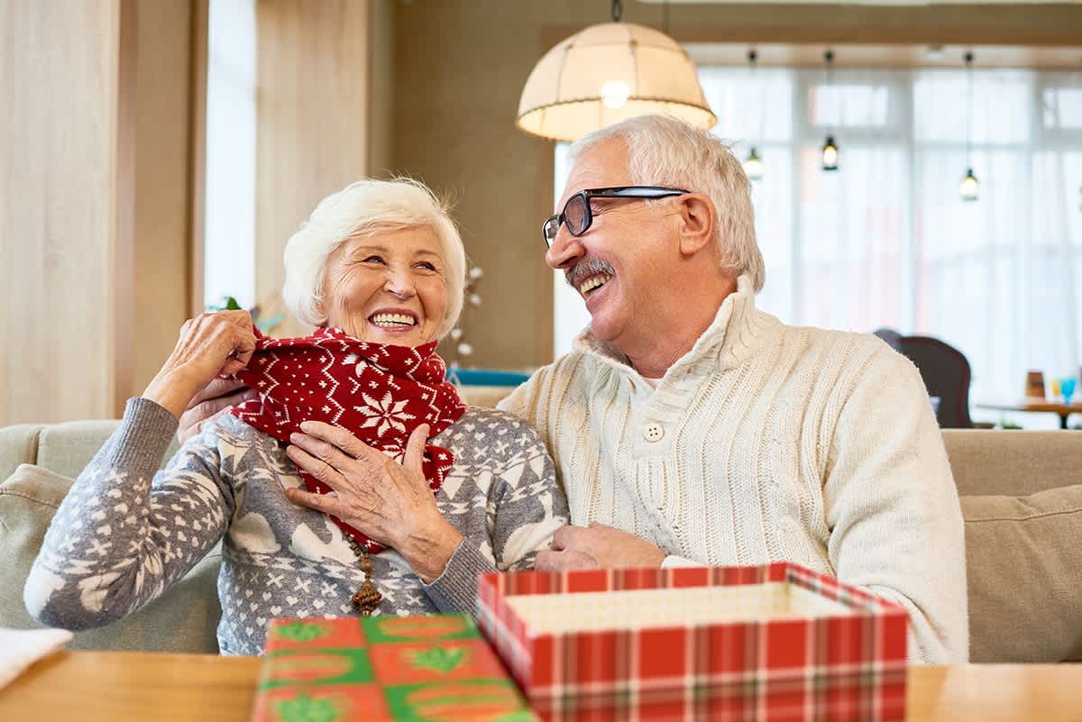 Elderly couple exchanging Christmas gift on couch