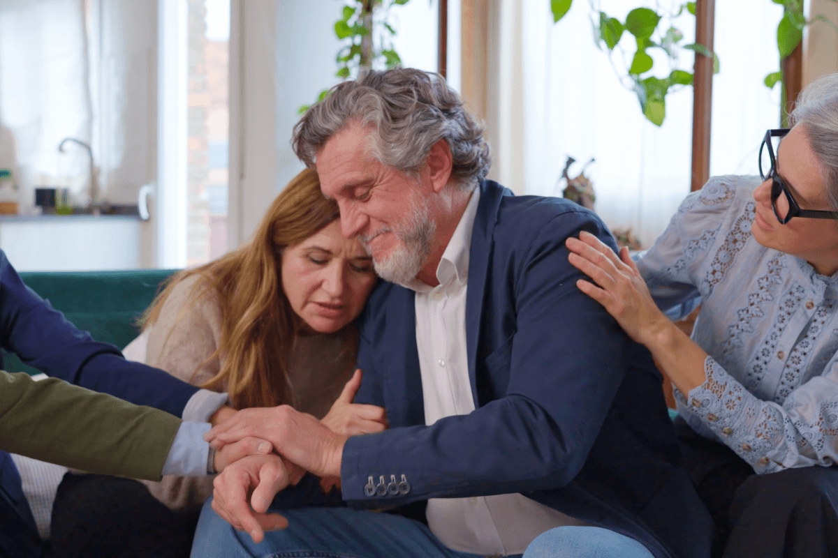 Friends comforting man during emotional moment indoors