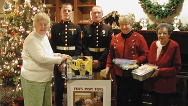 Group donating toys beside Christmas tree