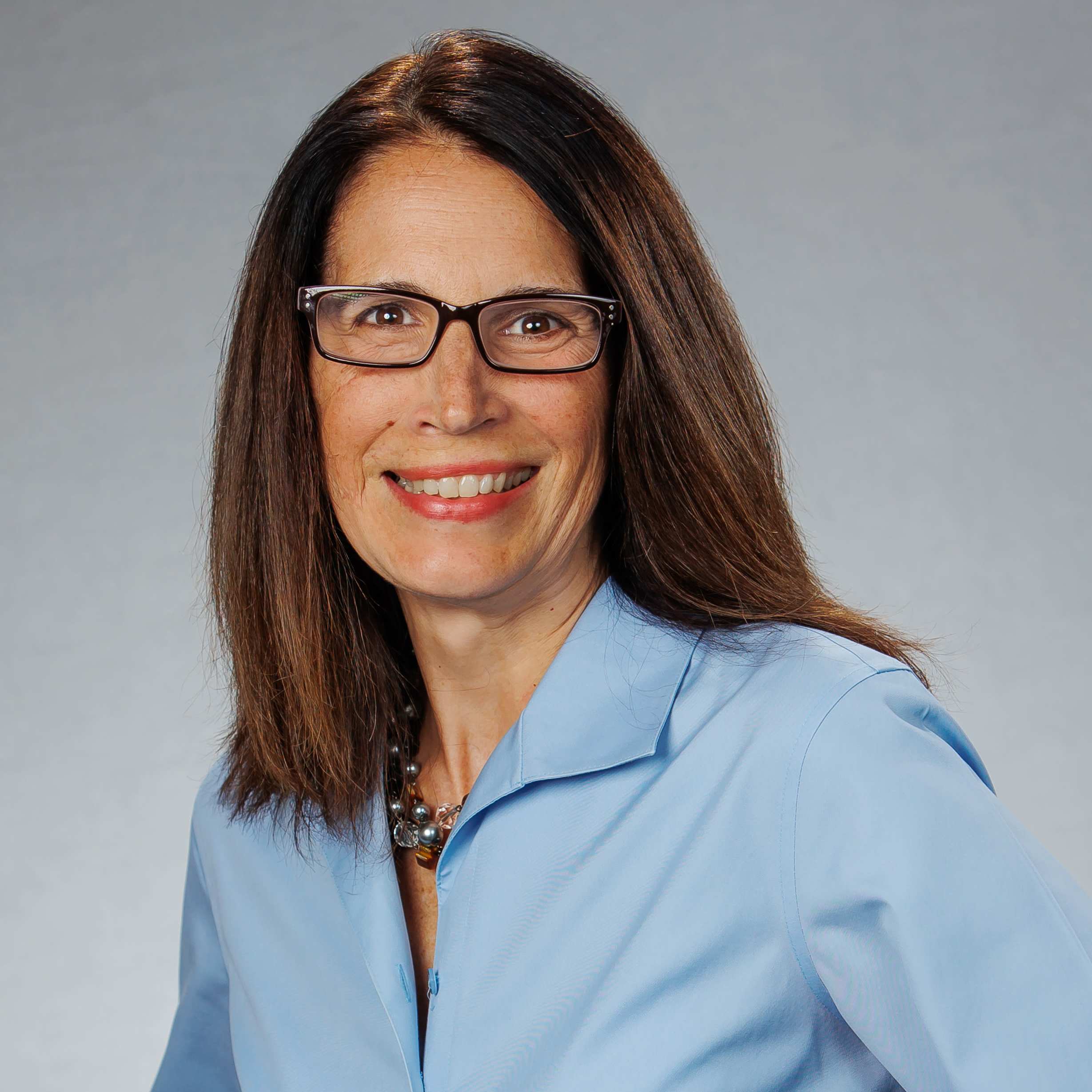 Professional headshot of woman wearing glasses and blue blouse