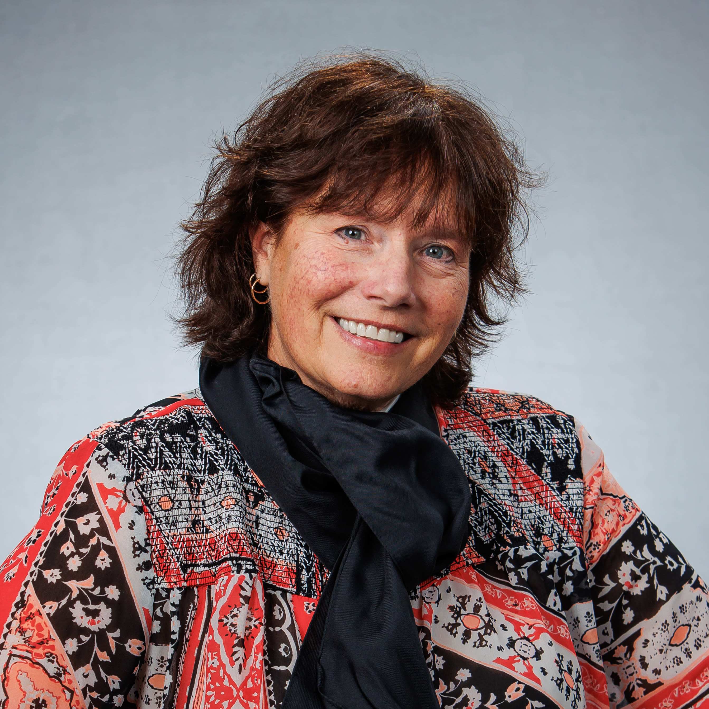 Smiling woman in patterned blouse and scarf