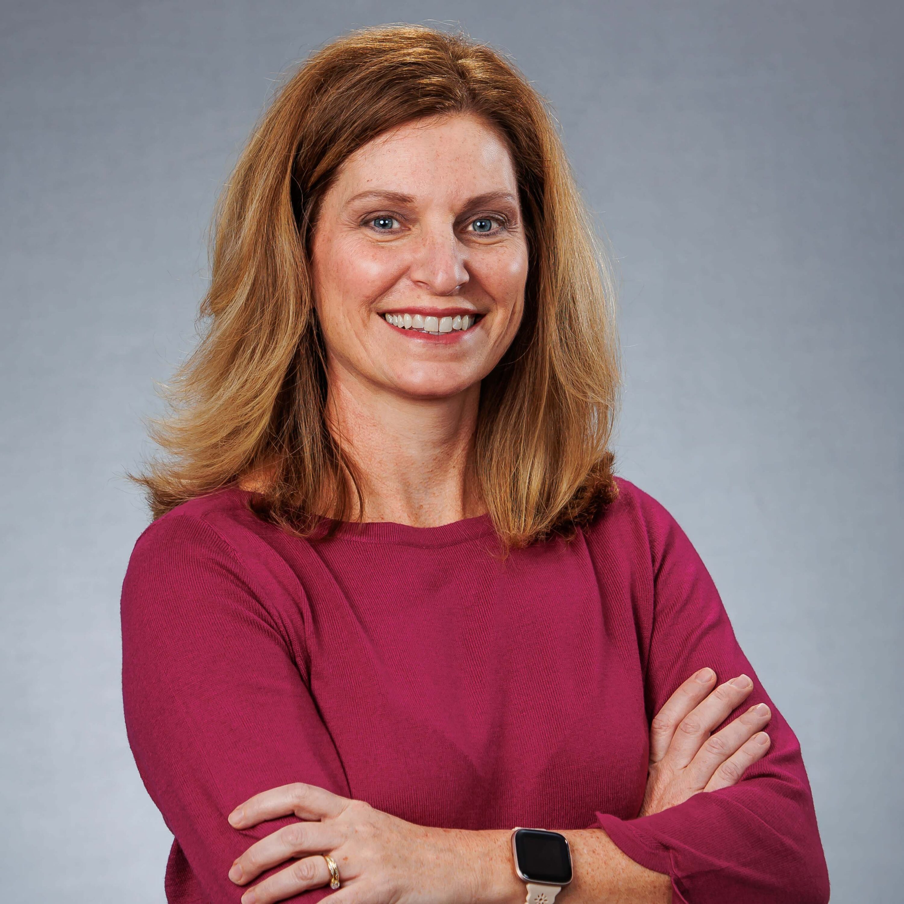 Smiling woman with arms crossed against gray background