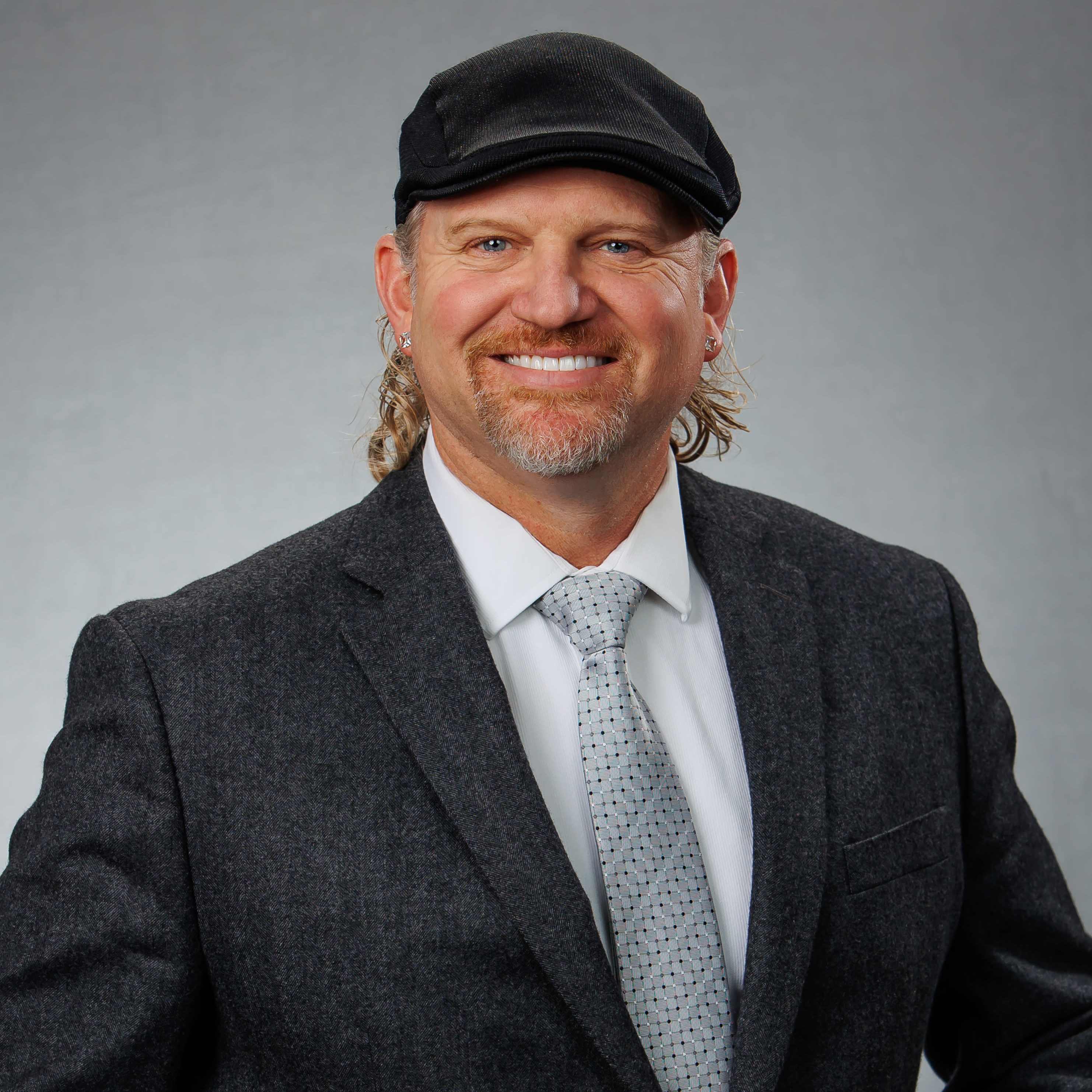 Smiling man in suit and black cap