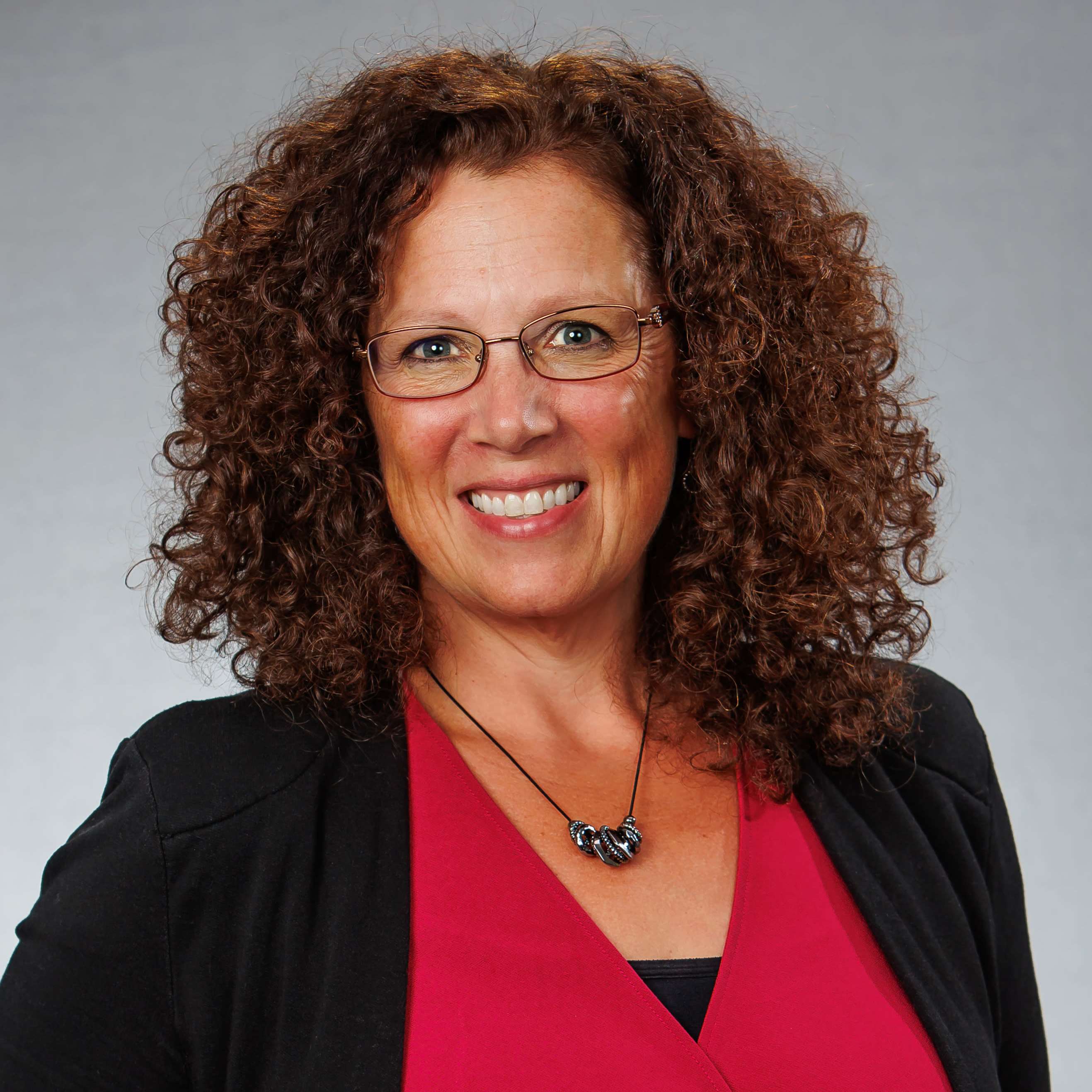 Smiling woman with curly hair and glasses