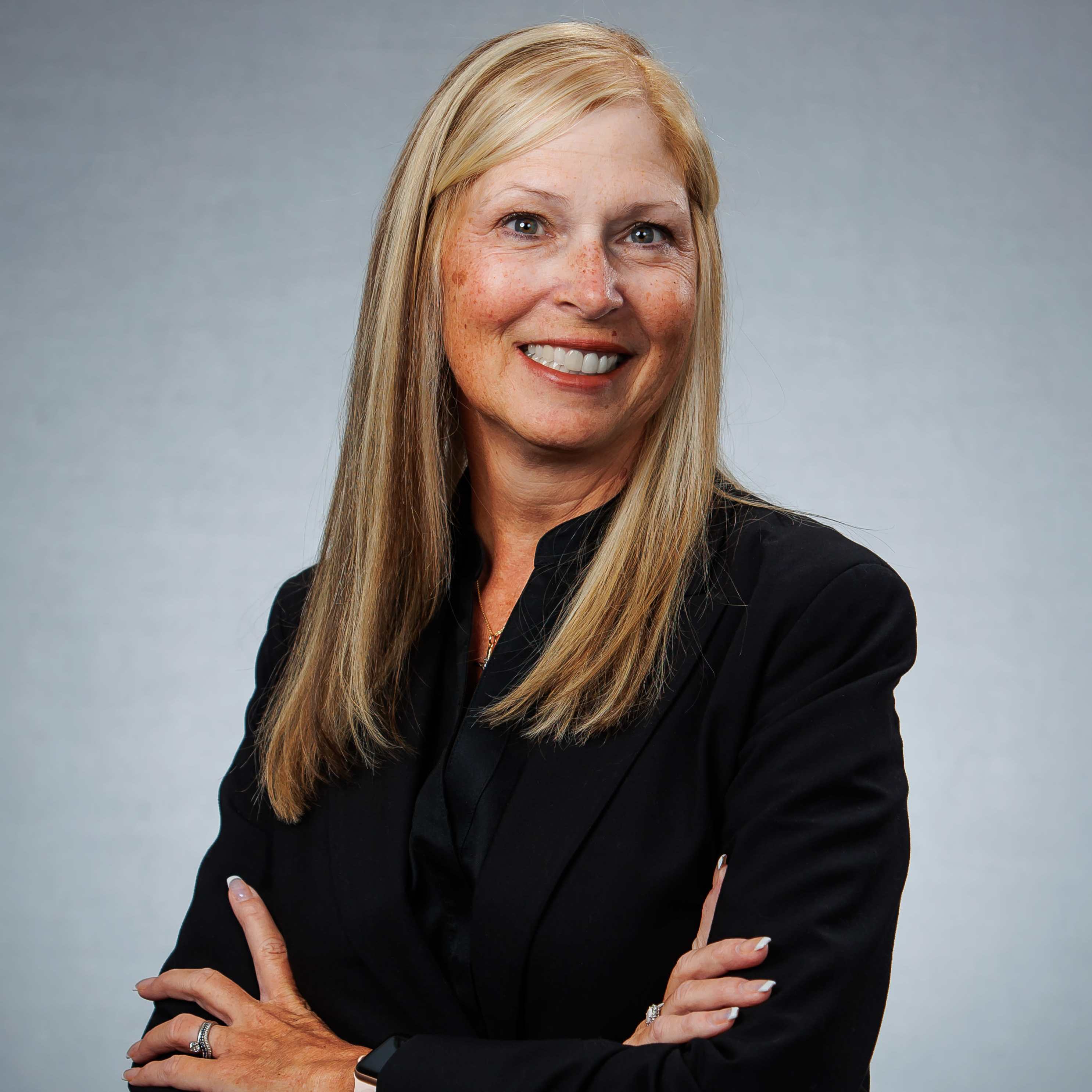 Smiling businesswoman with arms crossed against gray background
