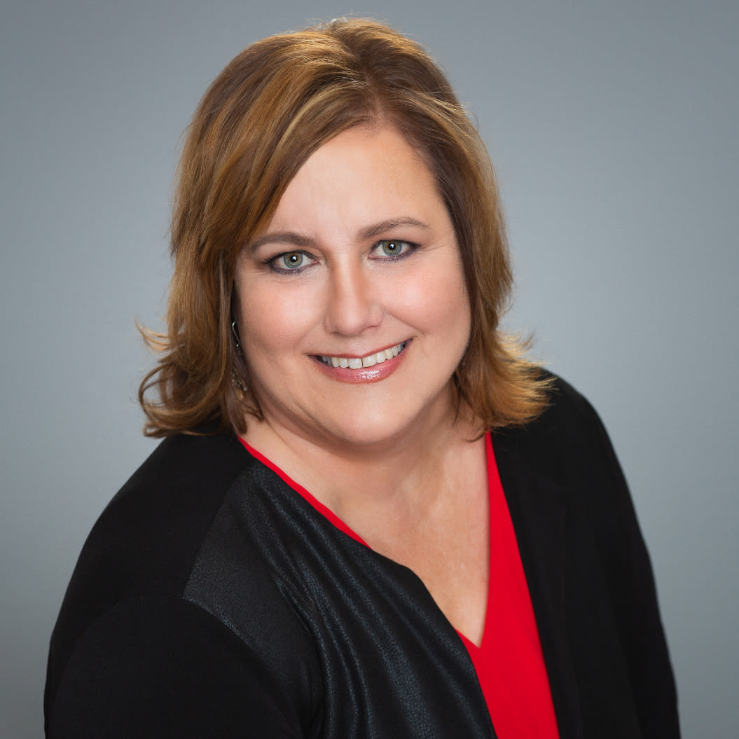 Professional headshot of smiling woman against gray background