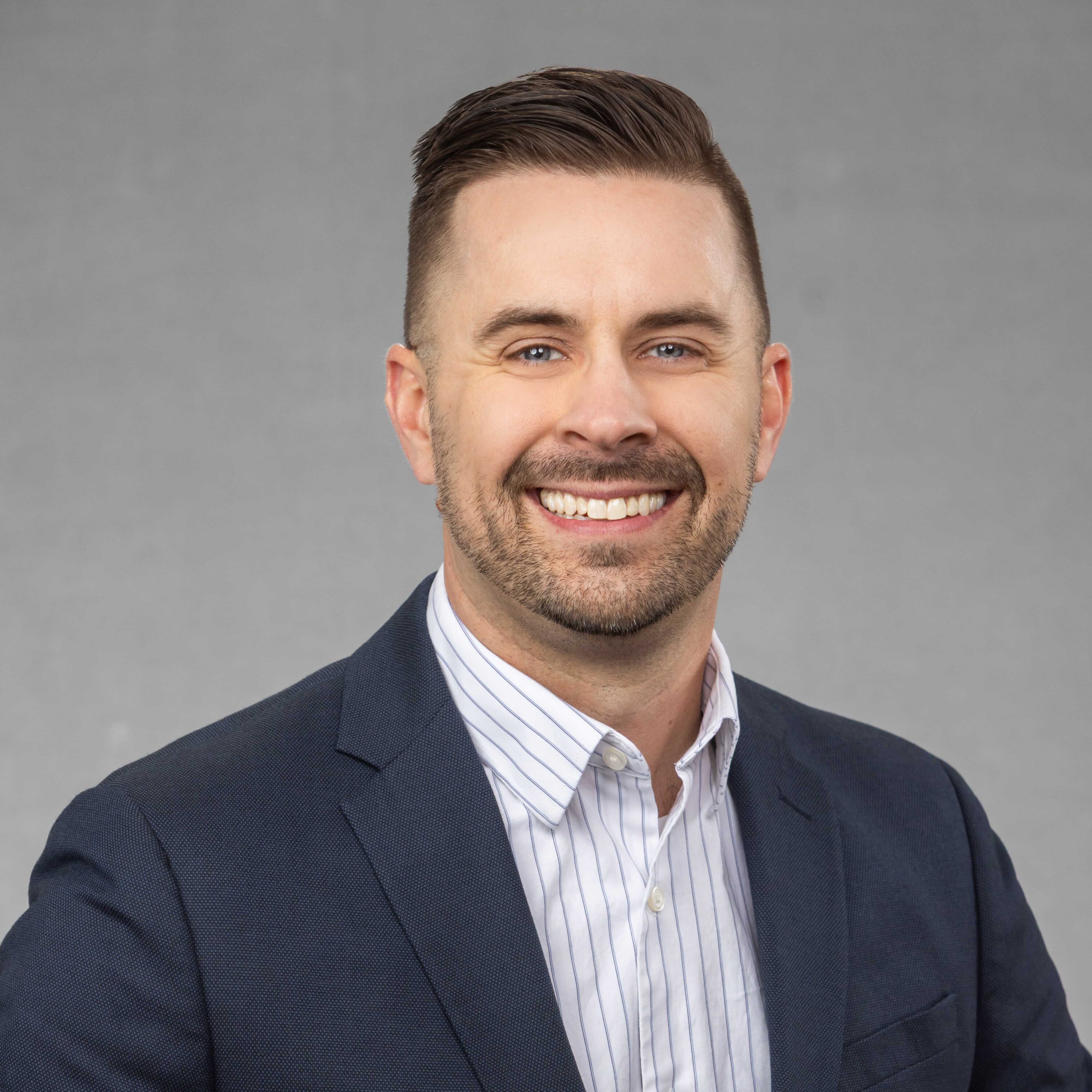 Smiling man in business suit against gray background