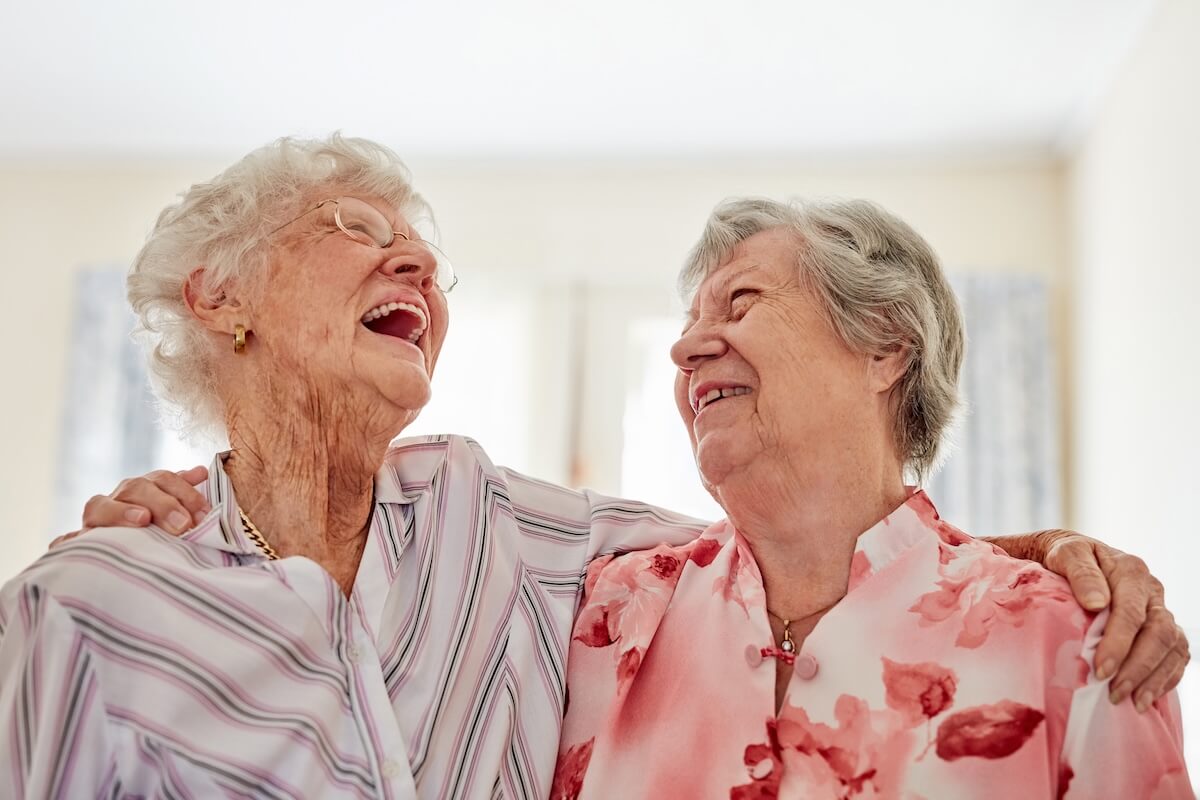 Two elderly women laughing together indoors