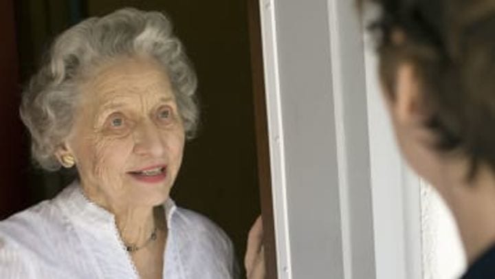 Elderly woman speaking to visitor at doorway