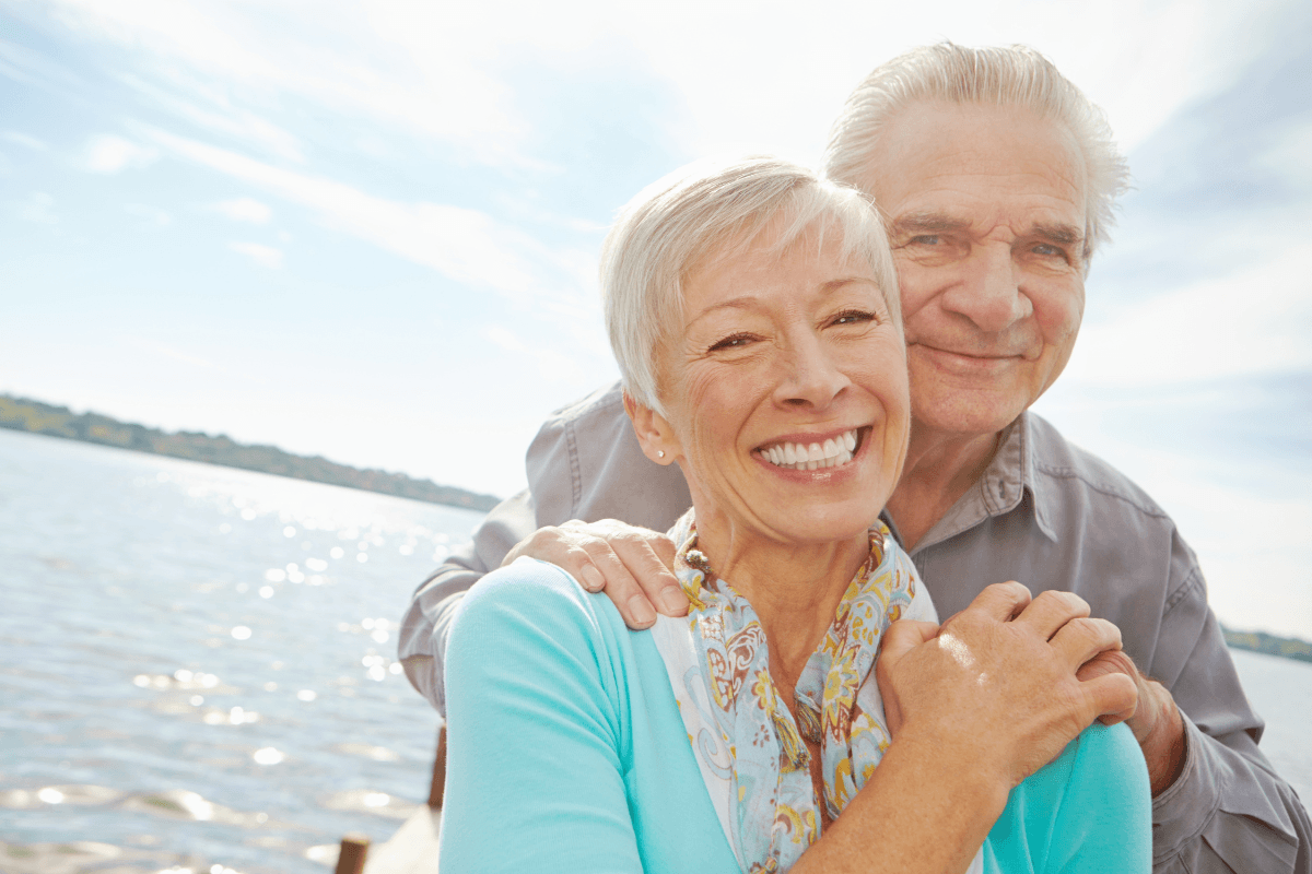 Smiling senior couple embracing by lakeside