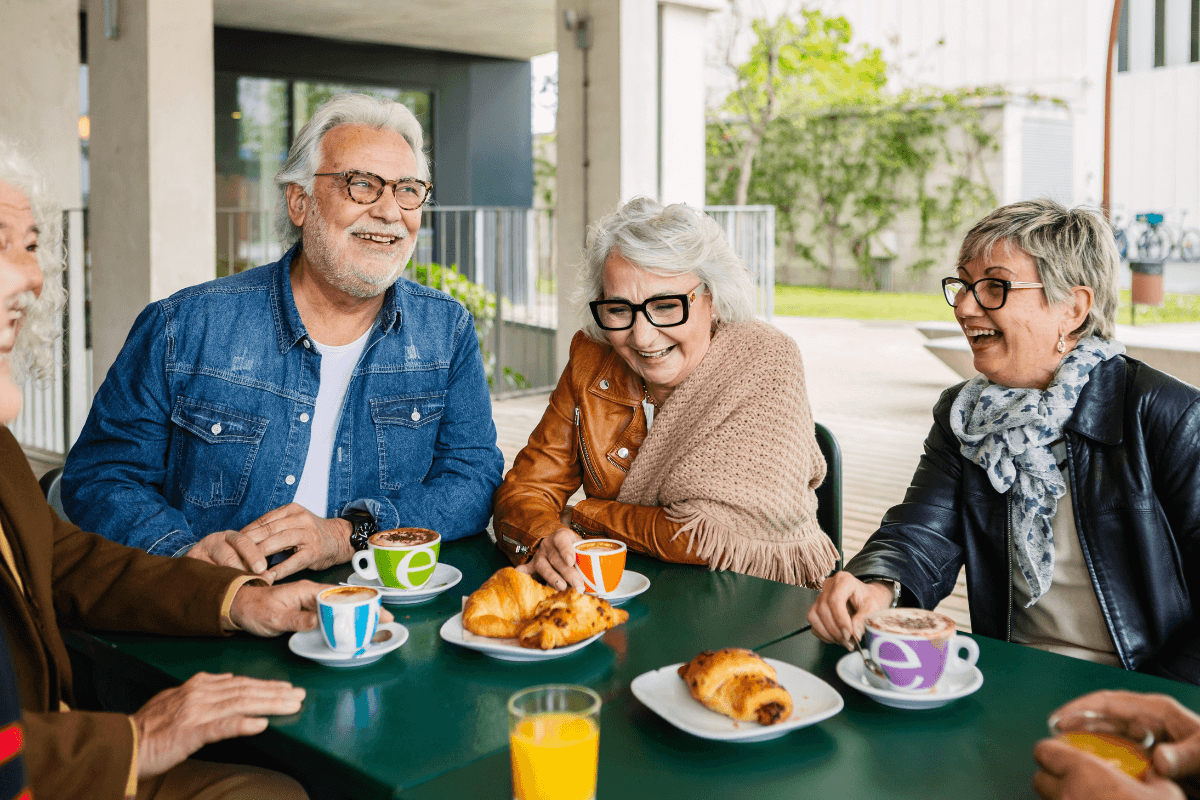 Four seniors laughing at outdoor cafe table