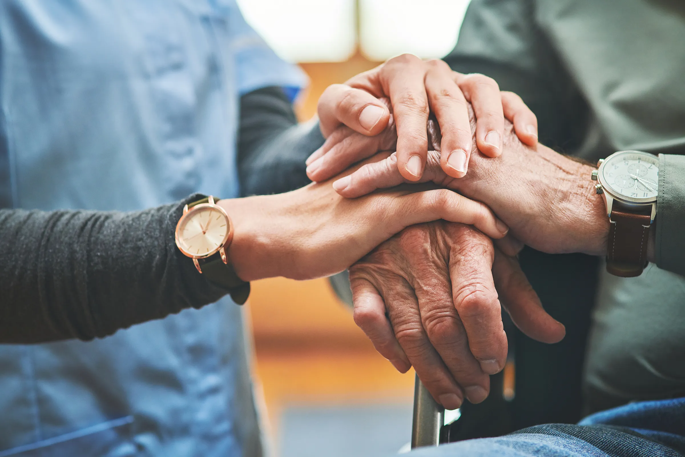 Caregiver holding elderly person's hands in support