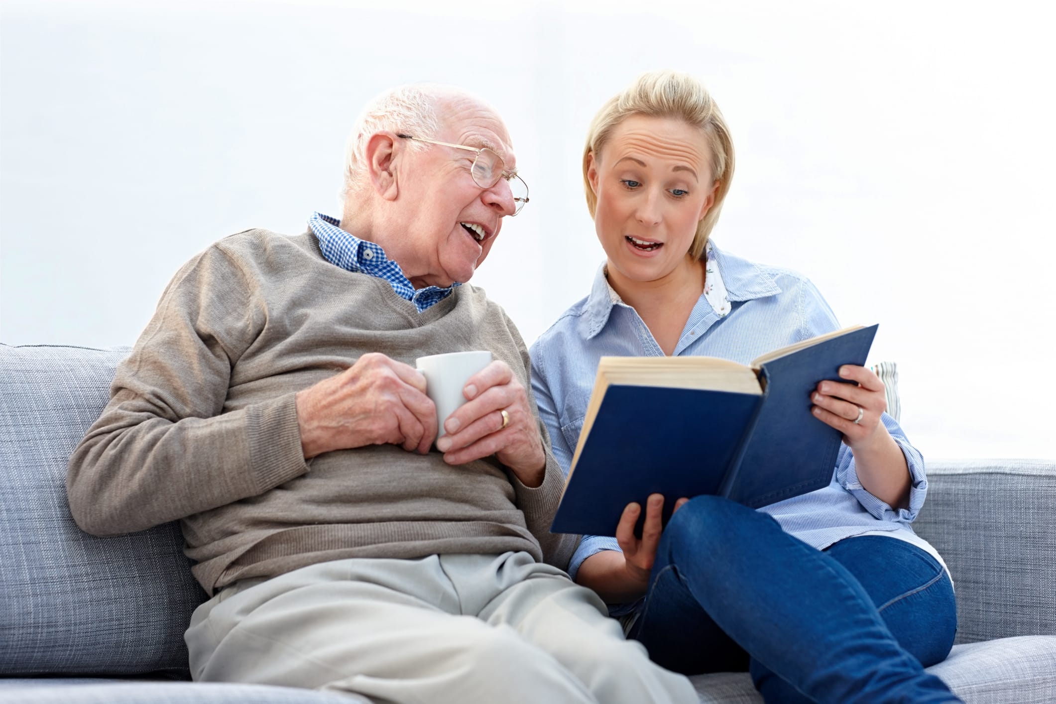 Woman reading book with elderly man on couch