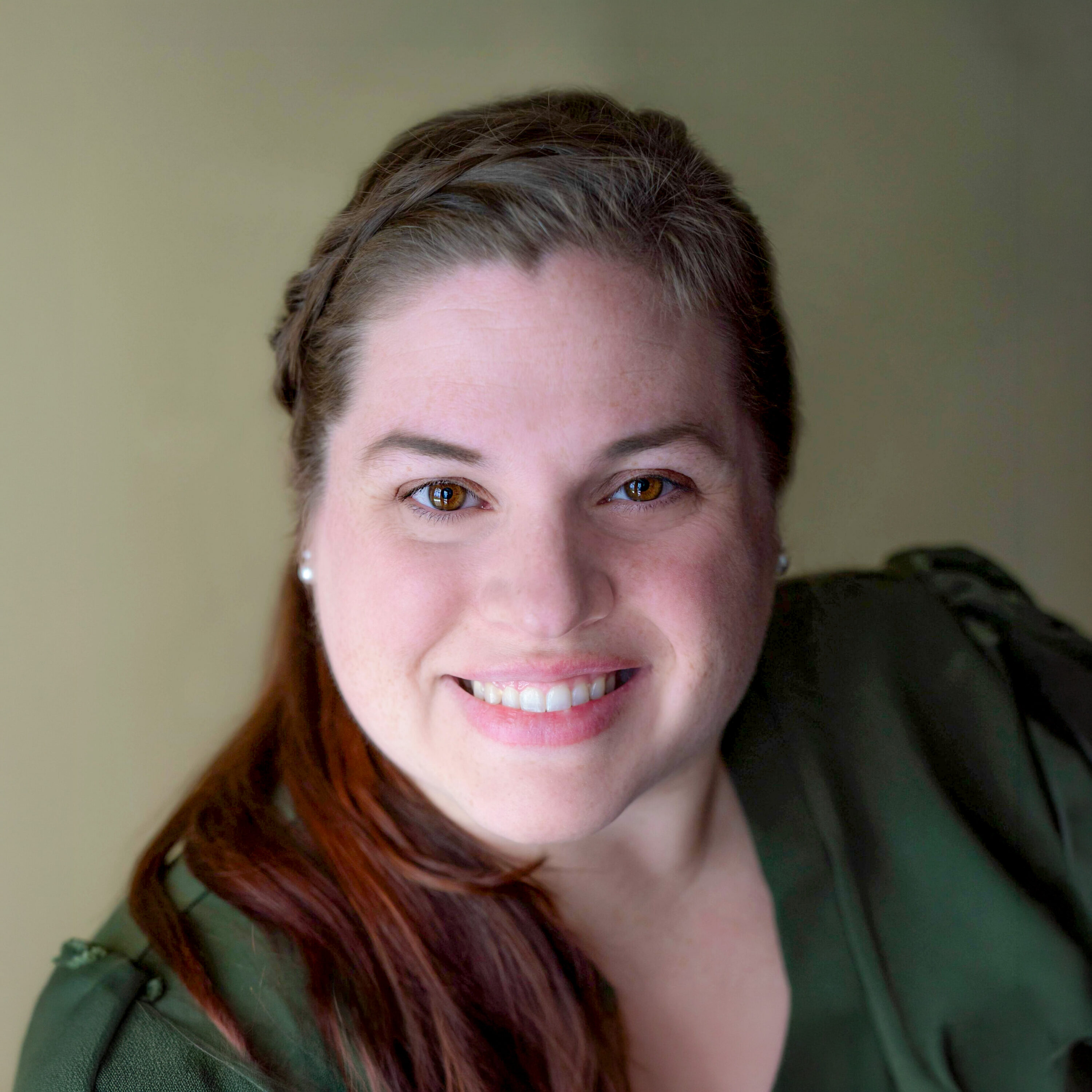 Smiling woman with braided hair and pearl earrings