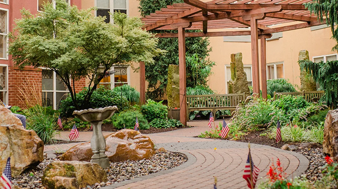 Landscaped courtyard with pergola, birdbath, and flags