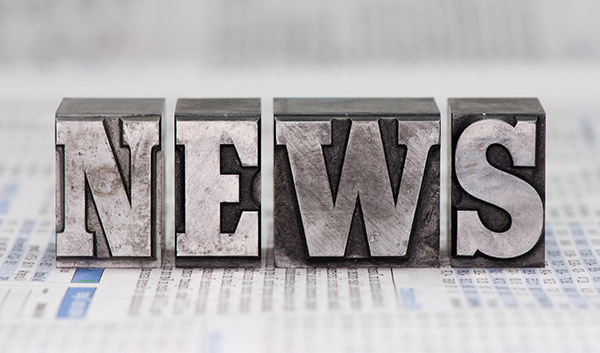 Metal letter blocks spelling NEWS on newspaper