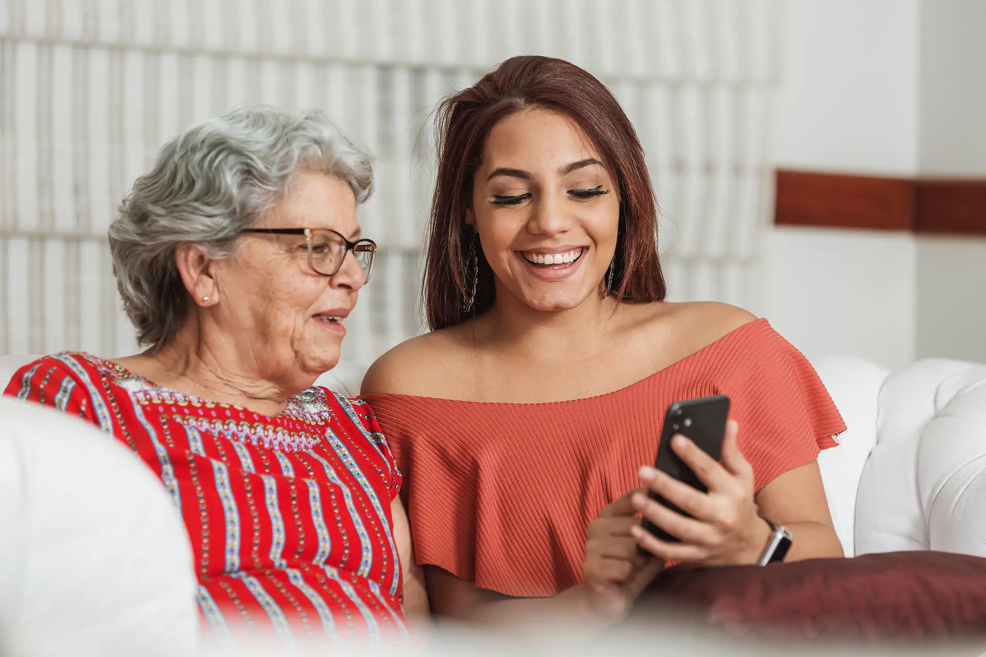Grandmother and granddaughter smiling at smartphone together