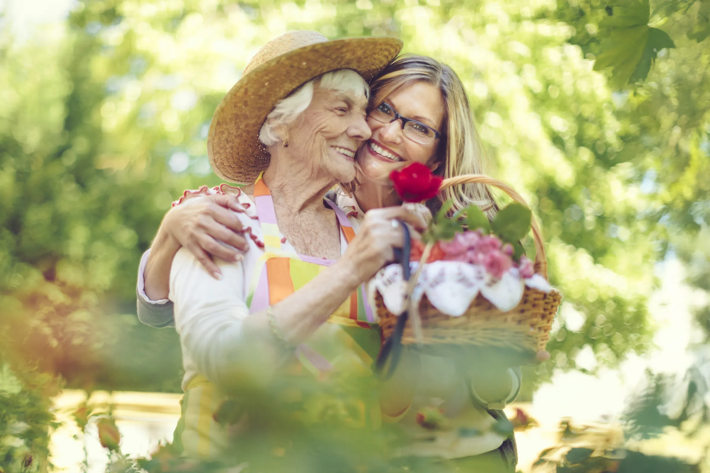 Daughter hugging elderly mother in sunny garden