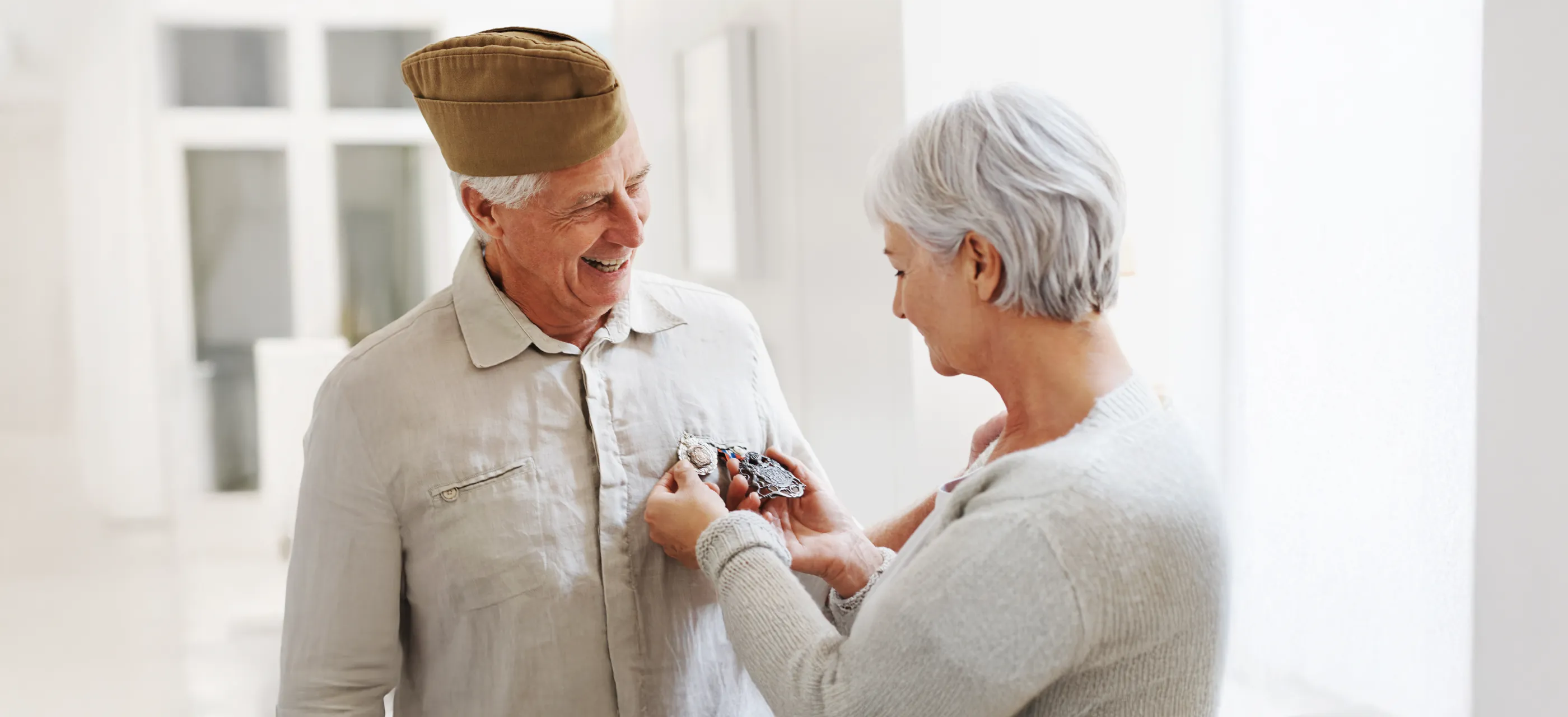 Elderly woman pinning medal on smiling veteran