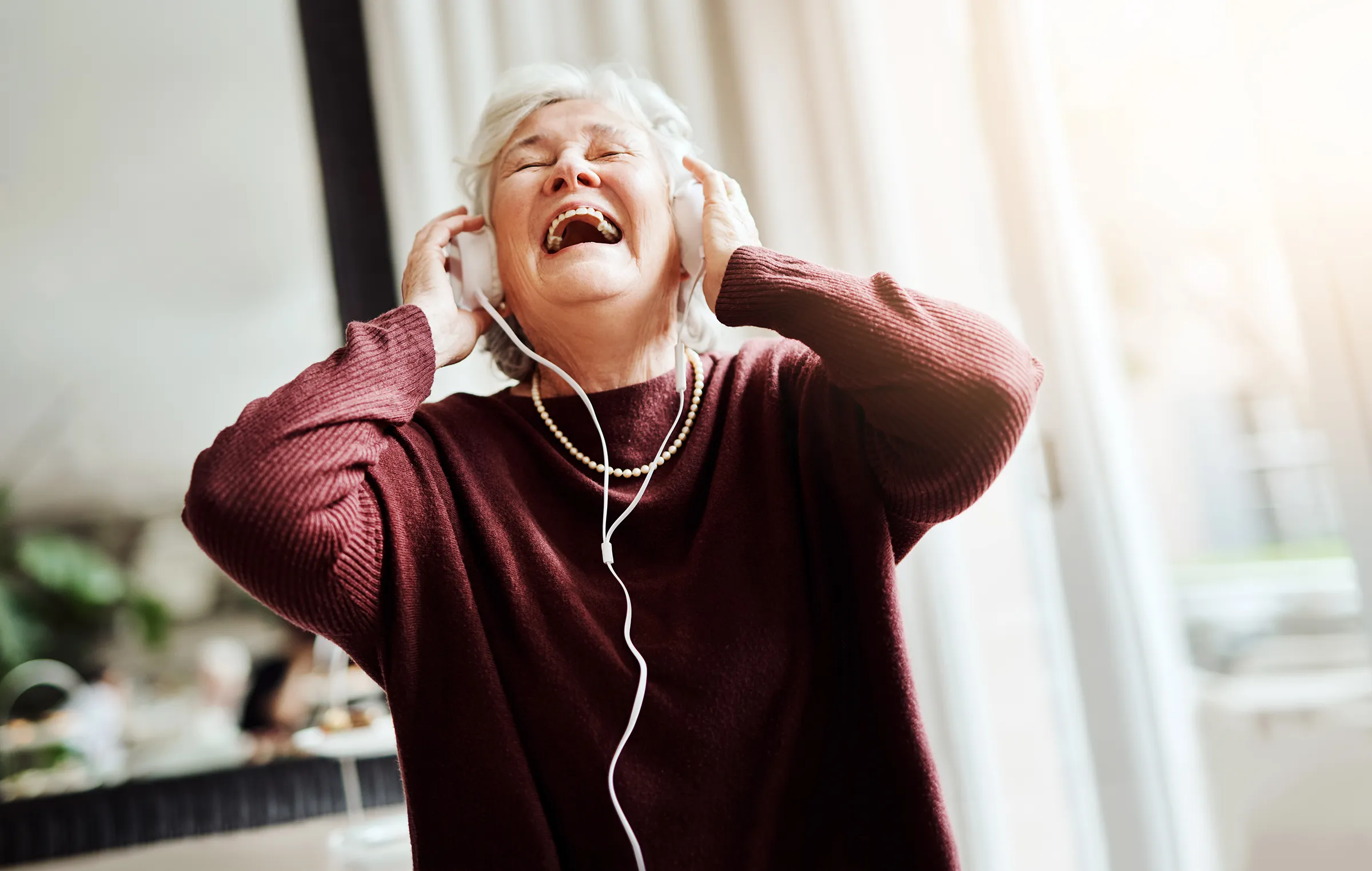 Elderly woman joyfully listening to music on headphones
