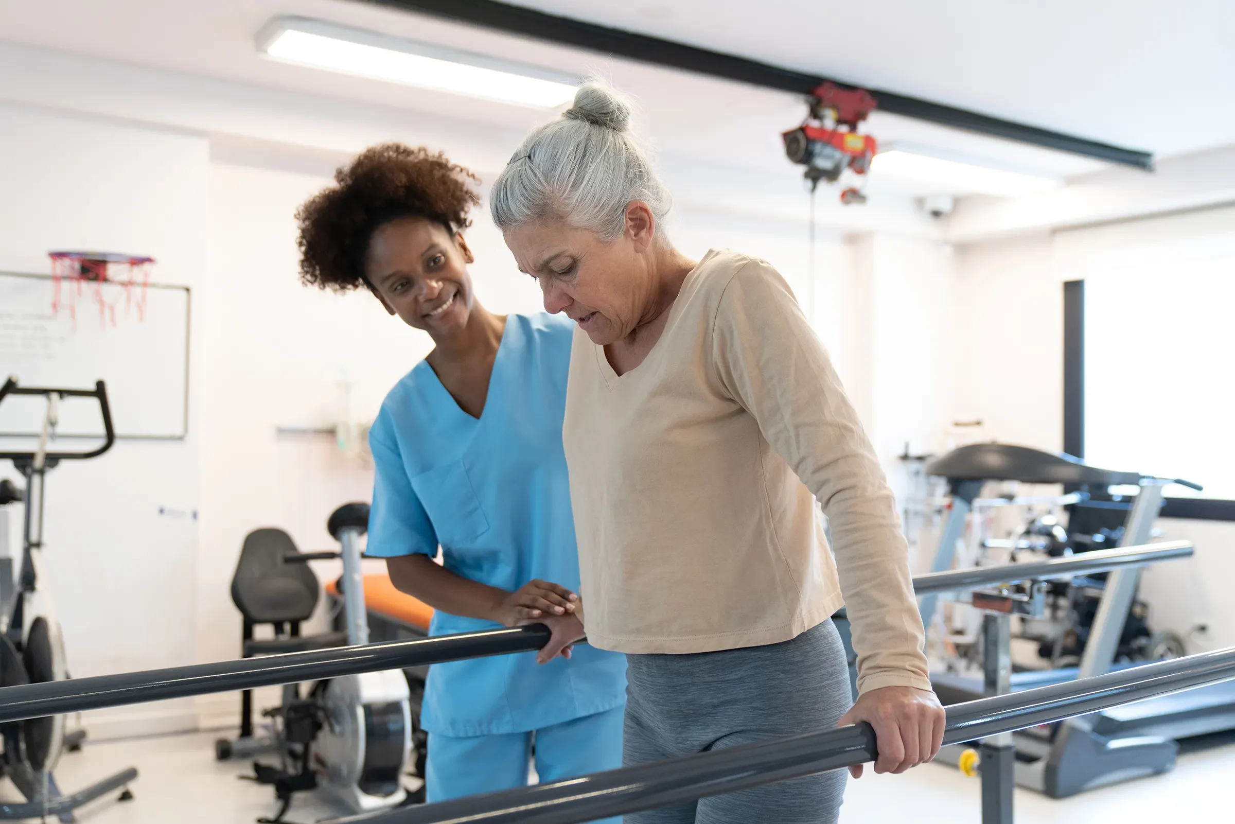 Senior woman practicing walking with therapist assistance